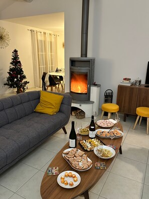 Ein gemütliches Wohnzimmer mit Kamin, einem für eine Mahlzeit gedeckten Esstisch und einem Weihnachtsbaum.