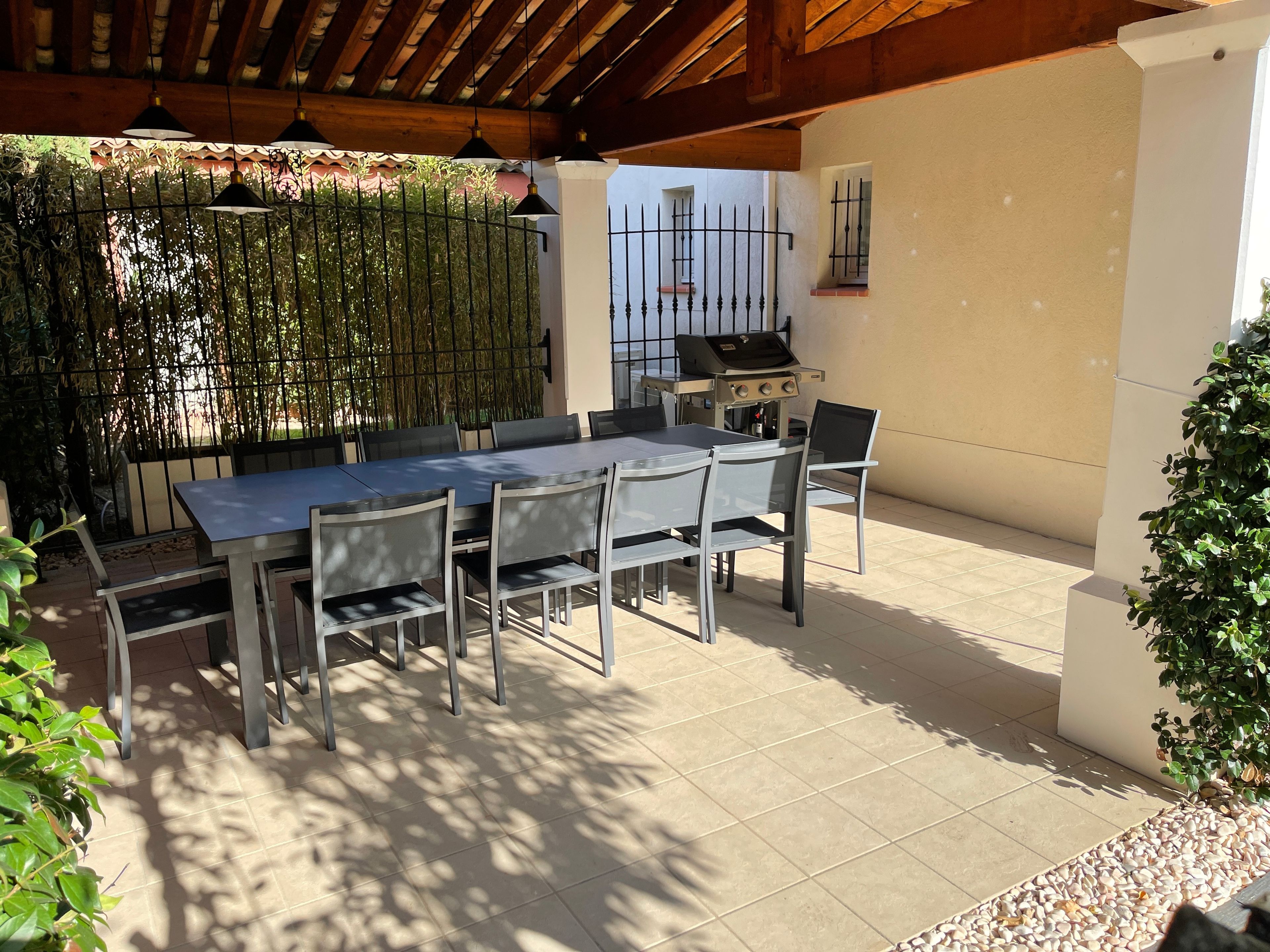 Un patio al aire libre con mesa y sillas, una parrilla y una cerca de bambú.