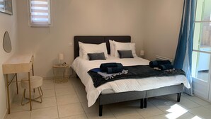 Une chambre à coucher avec un lit, des tables de chevet, un bureau et une fenêtre avec des rideaux.
