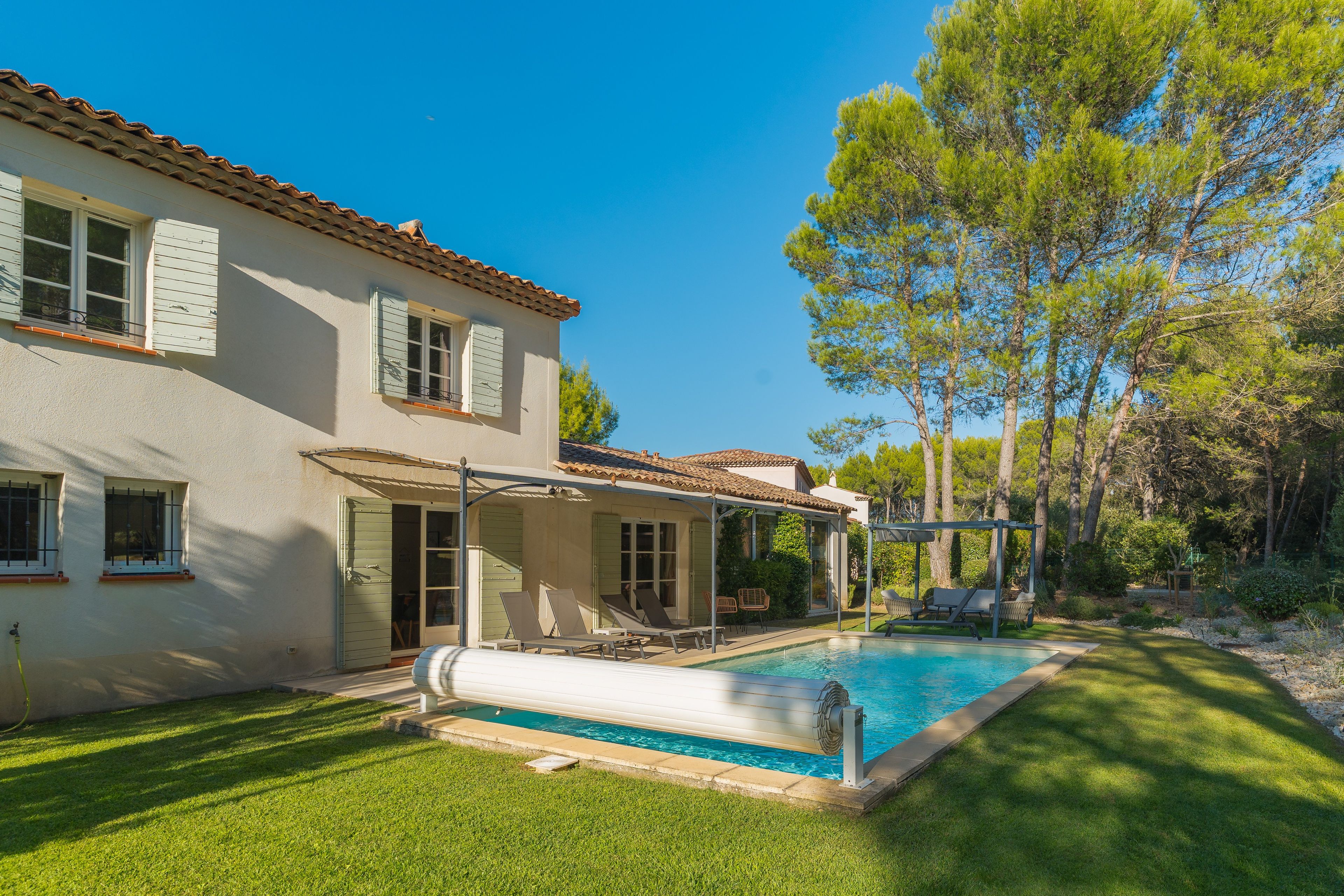 Una casa con piscina, patio cubierto y jardín.