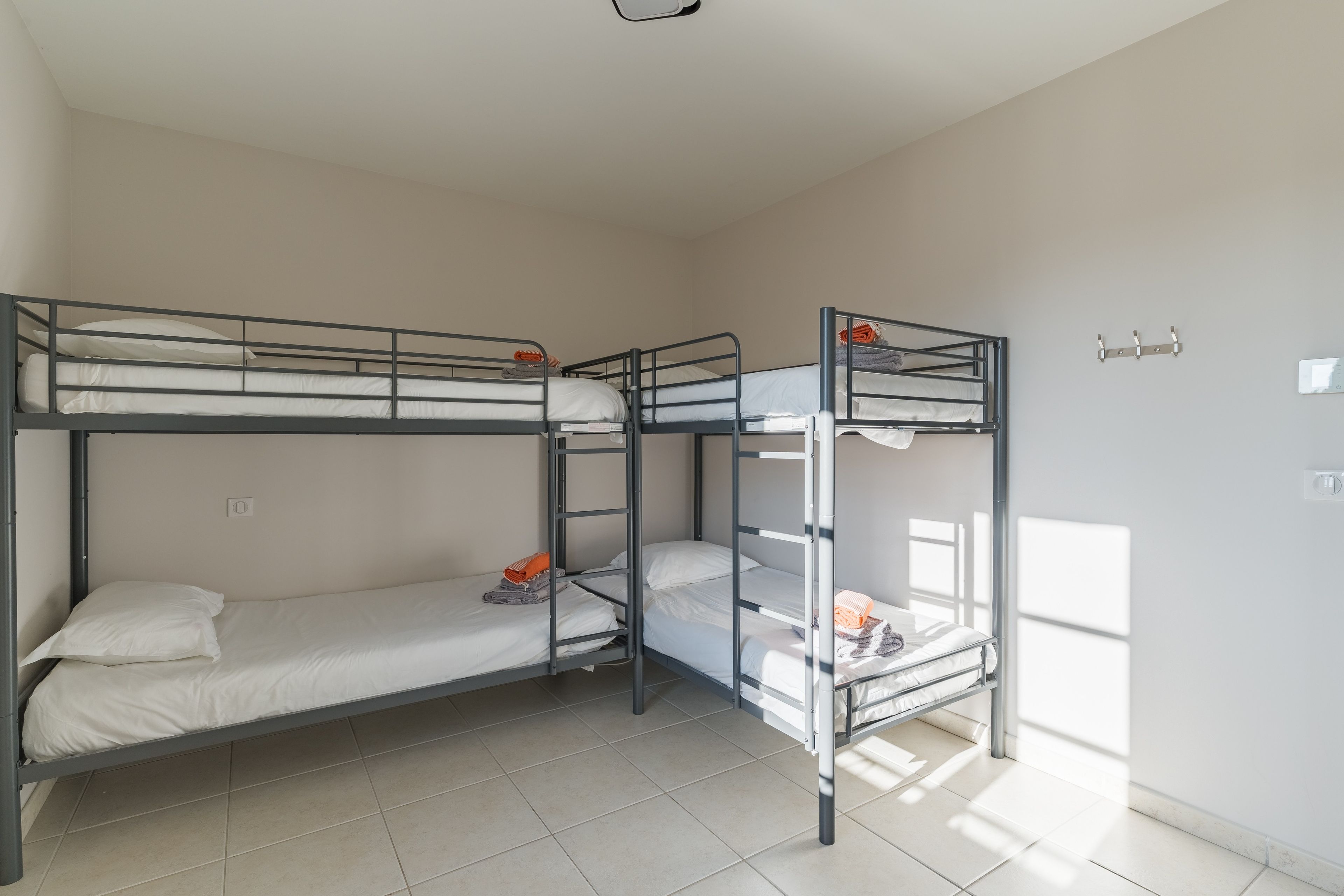 Ein Zimmer mit Etagenbetten, einem Fenster und einem an der Wand befestigten Lichtschalter.