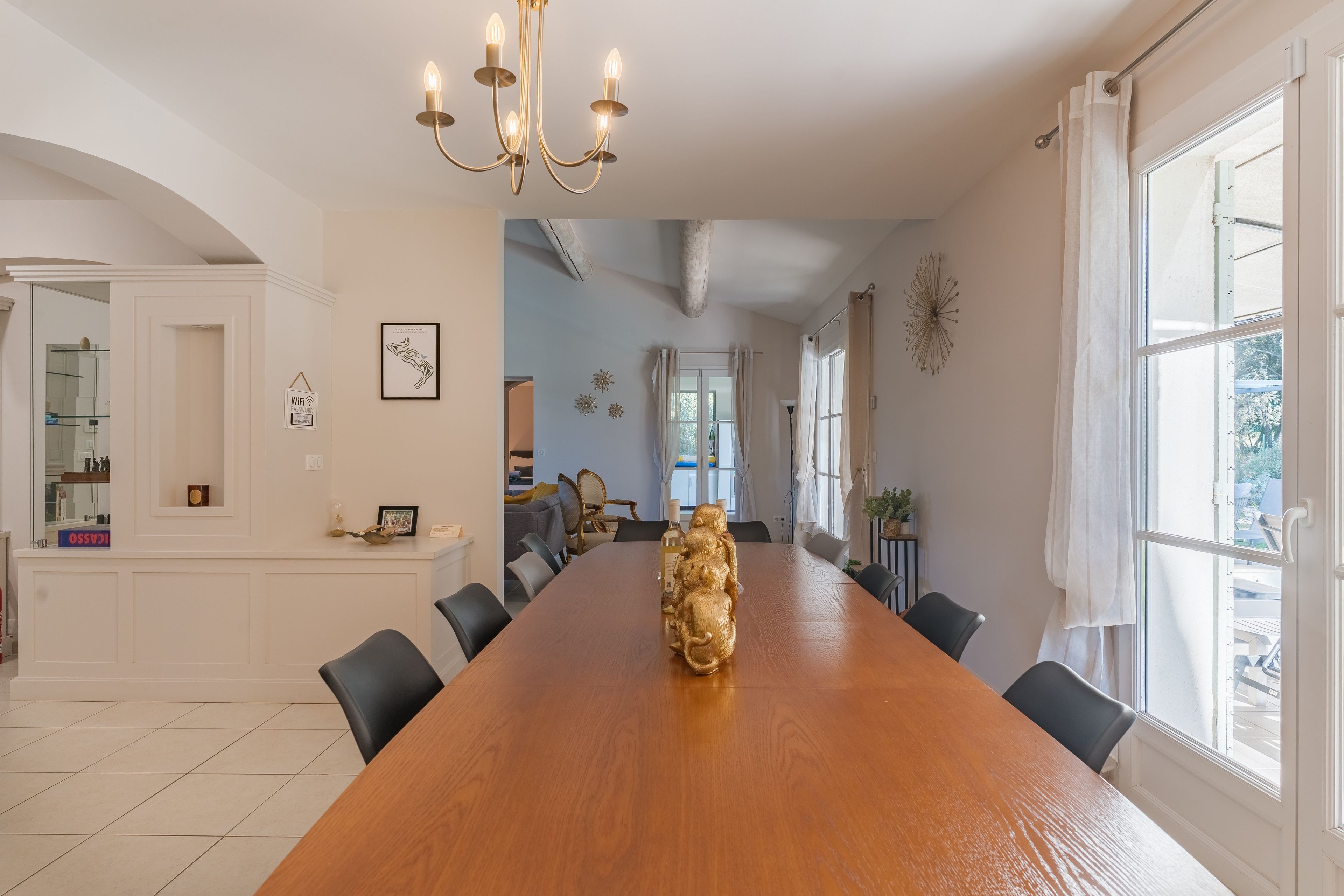 Une salle à manger spacieuse avec une longue table en bois, des chaises noires et un lustre.