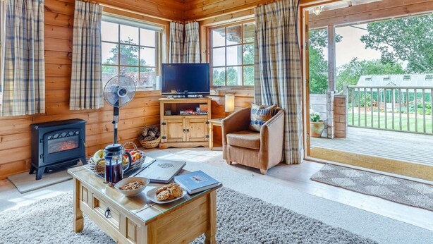 Ein gemütliches Blockhaus-Interieur mit Kamin, Fernseher und Sitzecke.