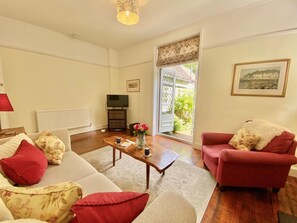 A living room with a sofa, armchair, coffee table, and a television. - 1 Bed in Ventnor (oc-ic144) (Ventnor)