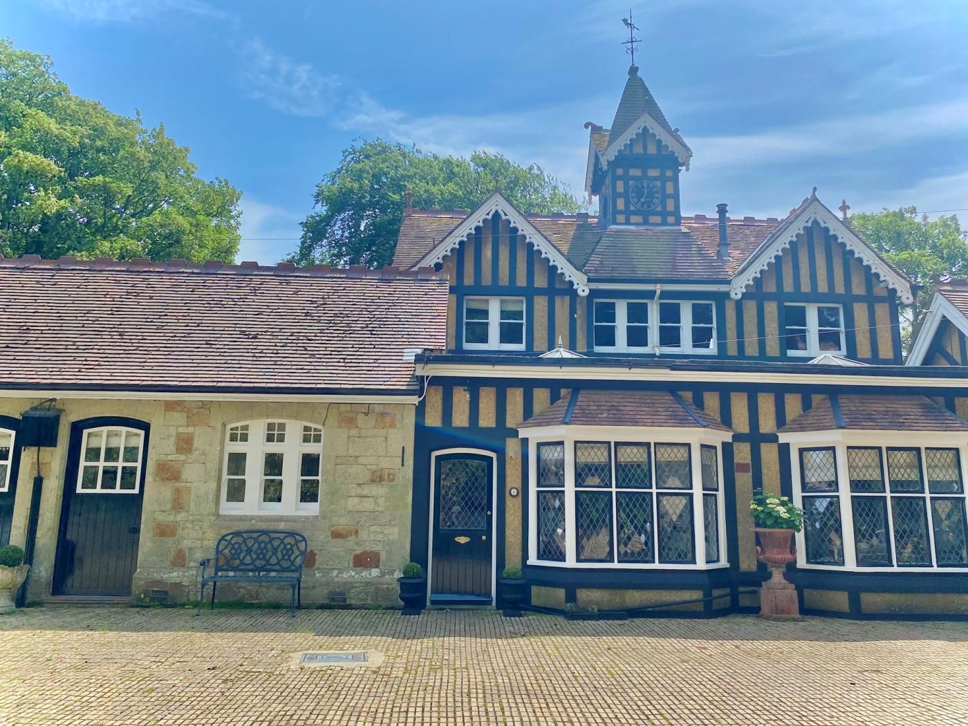 A traditional building with a prominent clock tower, stone facade, and a bay window.