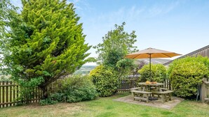 A backyard with a picnic table, a wooden fence, and various trees. - 2 Bed in Godshill (oc-ic129) (Godshill)