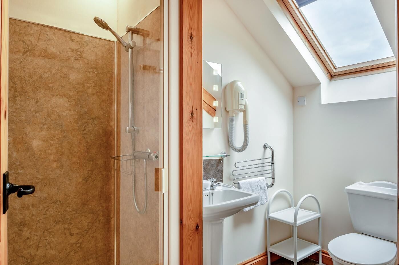 Un bagno con doccia, toilette, lavandino e un lucernario.