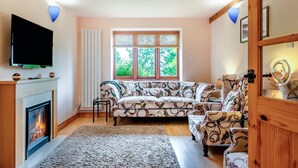 A living room with a fireplace, sofa, and television. - 2 Bed in Godshill (oc-ic129) (Godshill)