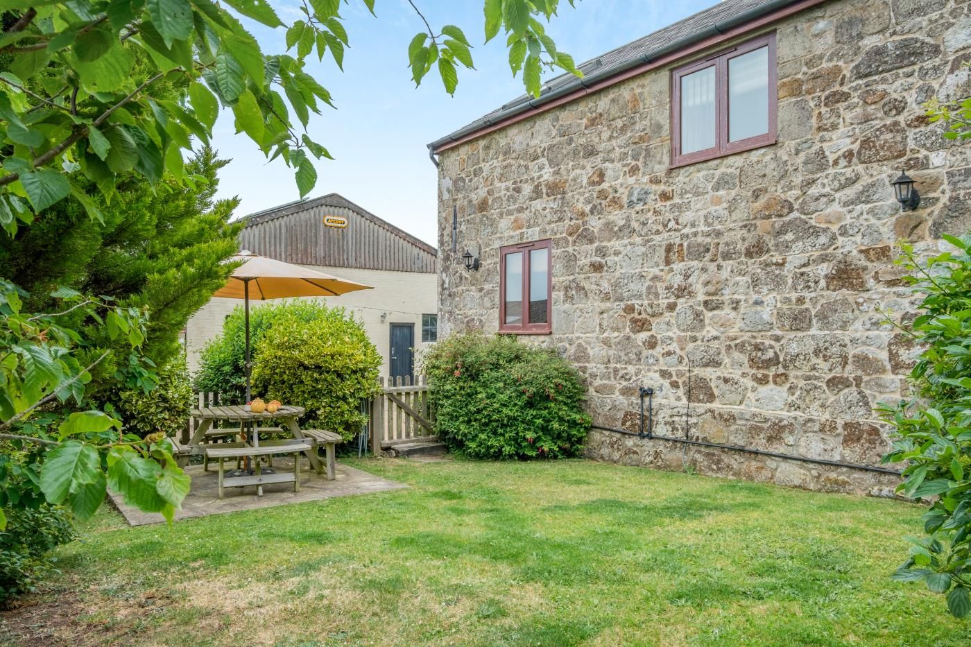 Un bâtiment en pierre doté d’une terrasse en bois et d’une table de pique-nique.