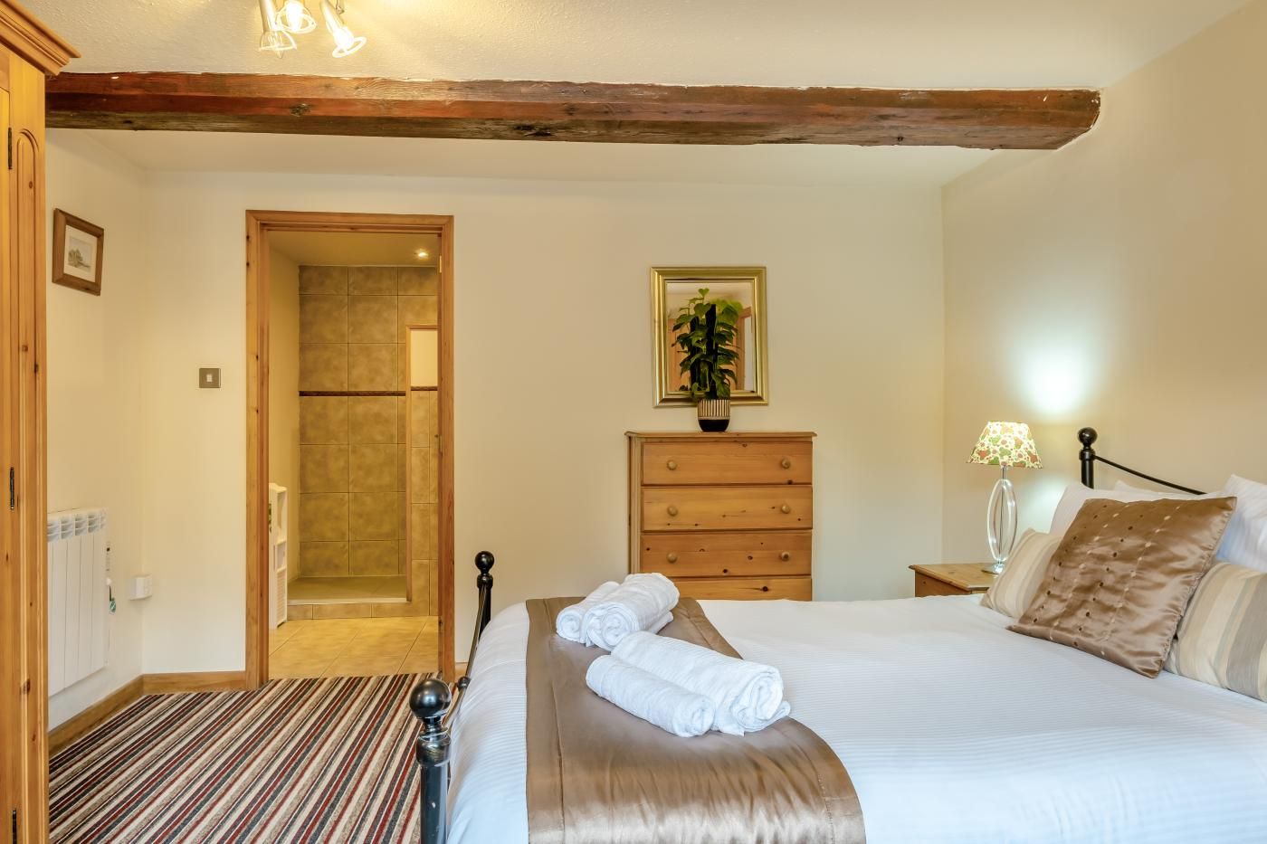 A hotel room with a bed, a dresser, a mirror, and a door leading to a bathroom.