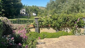 Ein Garten mit einer Steinsäule, einem Metallzaun und einem Haus im Hintergrund.