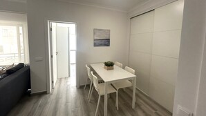 Ett kompakt bostadsutrymme med en matplats, en soffa och utsikt genom en öppen dörr.