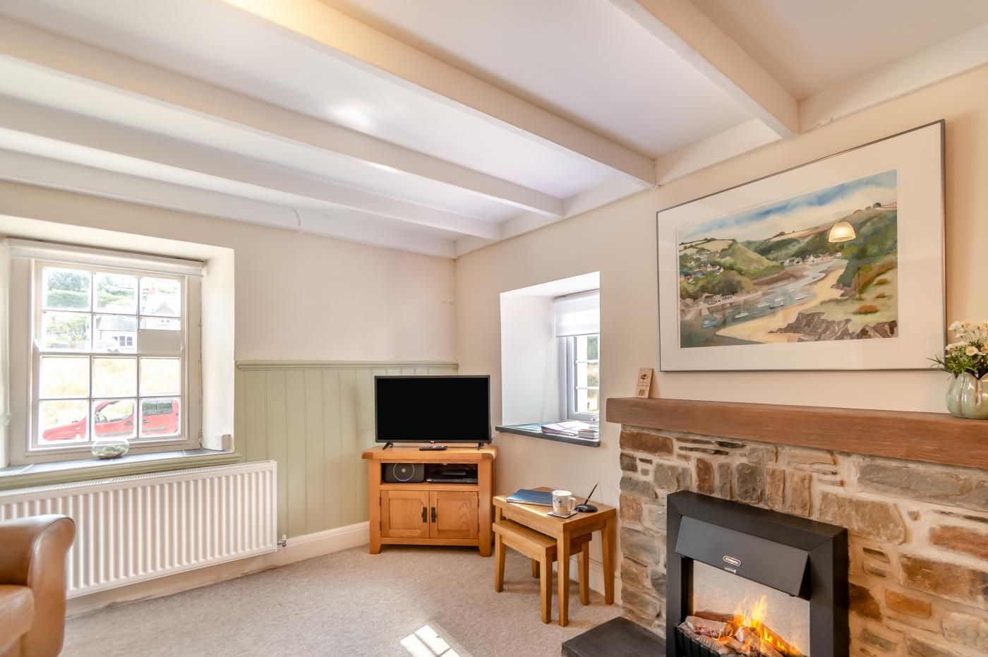 Un salon chaleureux avec une cheminée, un téléviseur et un tableau accroché au mur.