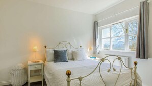 Een slaapkamer met een bed, nachtkastjes, een lamp, een raam en een radiator.