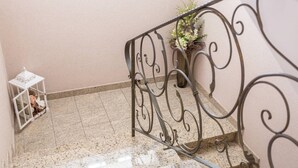 Vasemmalla on metallikaiteella varustettu portaikko, ruukussa oleva kasvi ja valkoinen lyhty.