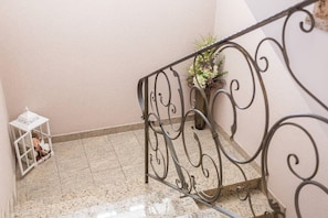 Eine Treppe mit Metallgeländer, einem Blumentopf und einem weißen Laternenlicht auf der linken Seite.