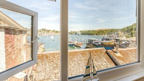 Une vue depuis une fenêtre donnant sur un port, avec des bateaux et un navire amarré.