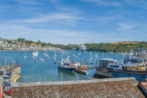 A harbor with multiple boats, a large cruise ship, and a building labeled 'Toms & Son.' - 2 Bed in Polruan (oc-pc023) (Fowey)