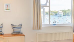Une pièce avec vue sur un port, un radiateur et des coussins à rayures posés sur une table.