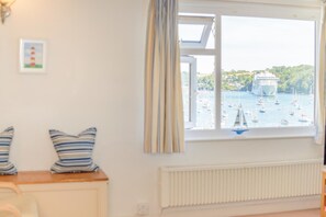 A room with a view of a harbor, a radiator, and striped pillows on a table. - 2 Bed in Polruan (oc-pc023) (Fowey)