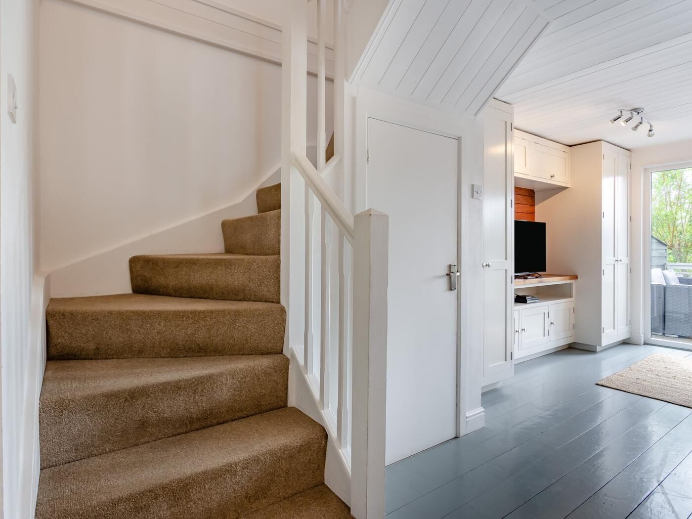 A staircase with carpeted steps leading to a room with white walls and a door leading to a balcony.
