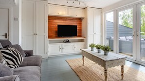A living room with a built-in TV, a sofa, a coffee table, and a sliding glass door leading to an outdoor area.