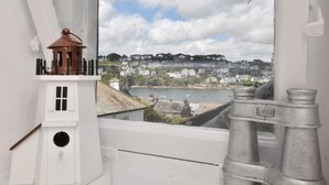 Ein Zimmer mit Blick auf eine Stadt, ein kleiner, turmartiger Bau und ein Fernglasbrett auf dem Fensterbrett.