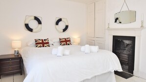 Ein Schlafzimmer mit einem großen Bett, Nachttischlampen, einem Kamin und einer Deckenleuchte.
