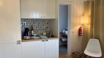 Eine kleine Küche mit einer gefliesten Spritzschutzwand, einer Holz Arbeitsplatte und einem weißen Stuhl.