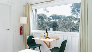 Una stanza con finestra, un tavolo, due sedie, una lampada e un estintore.