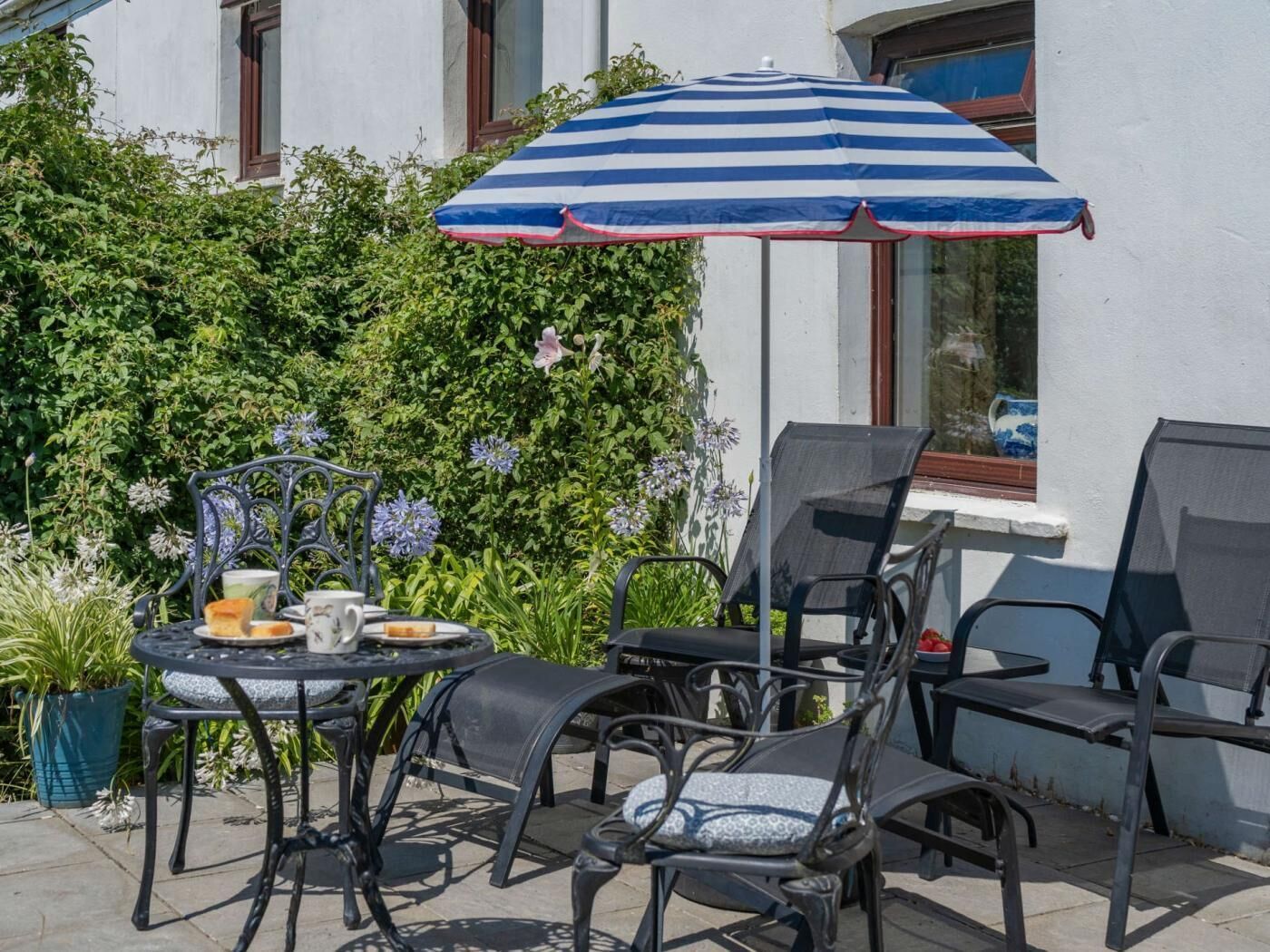 An outdoor patio with a table, chairs, and a striped umbrella.