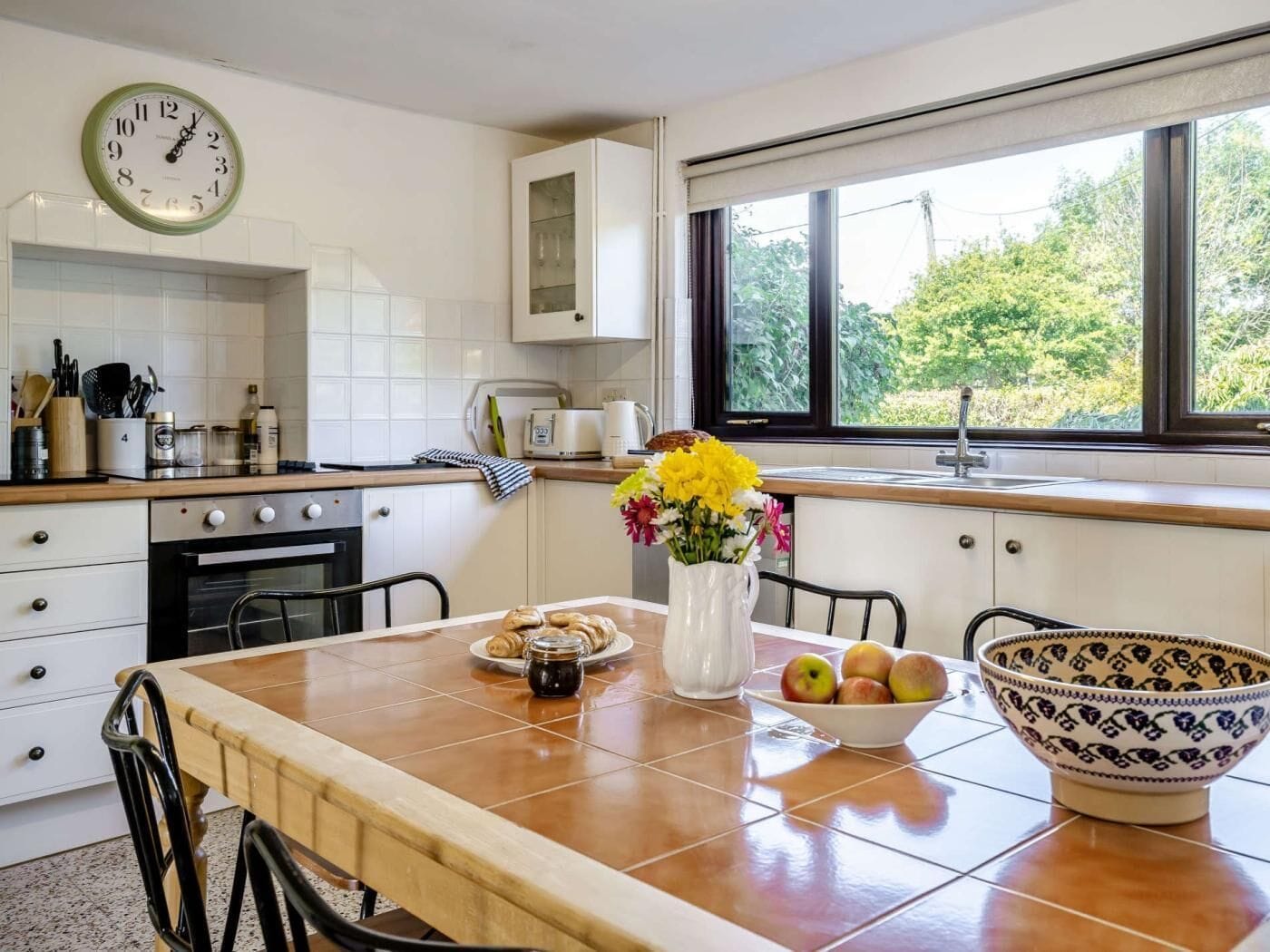 A kitchen with a stove, oven, and a window with a view of greenery.