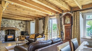 Un accogliente soggiorno con camino in pietra, divano in pelle, tavolo da pranzo in legno e un grande orologio.
