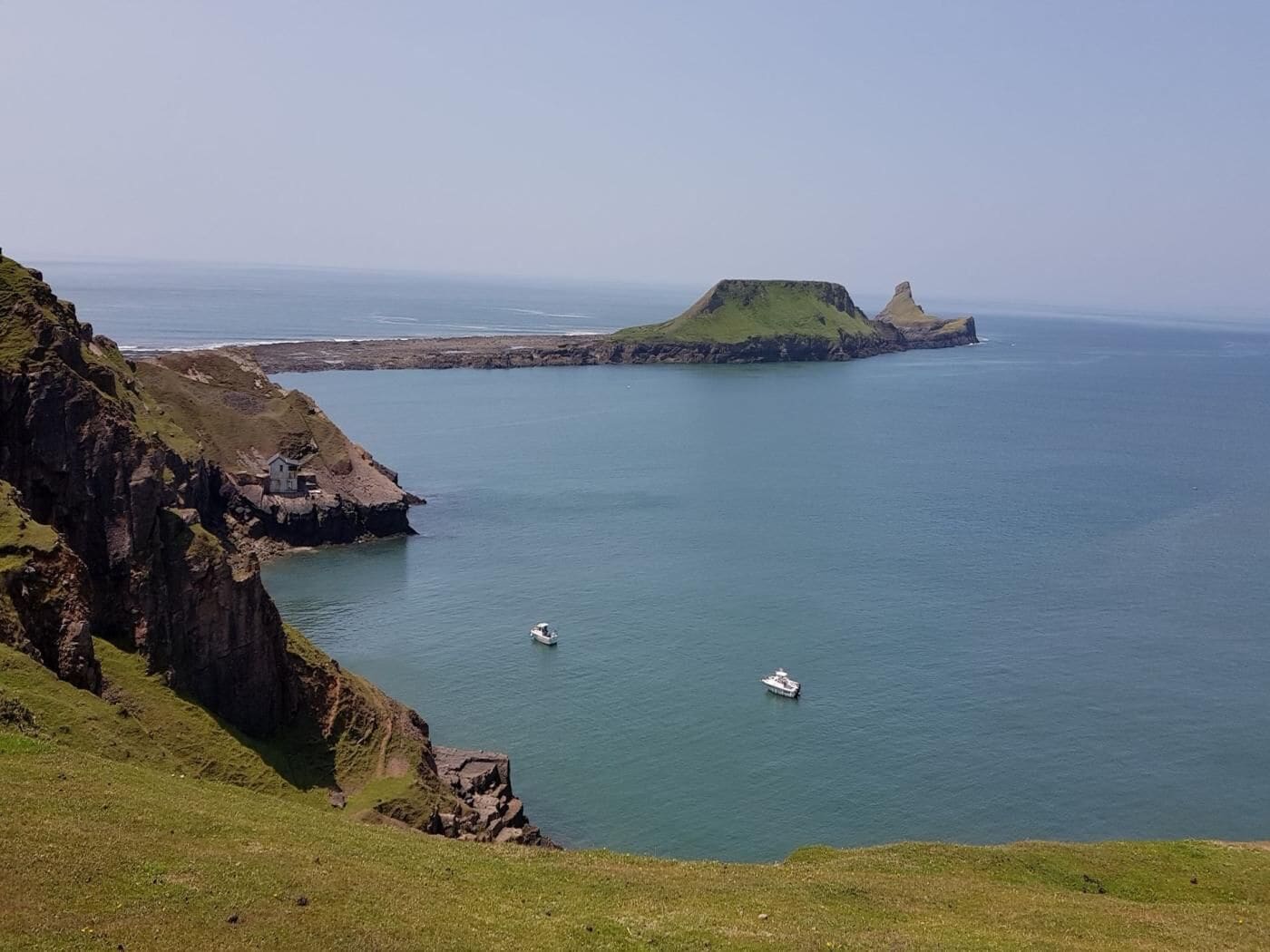 A coastal landscape with cliffs, a small boat, and a distant island.