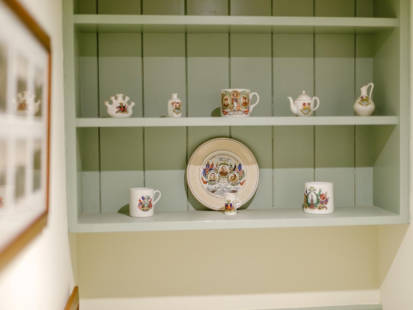 A shelf with various ceramic items including cups, a plate, and a teapot.
