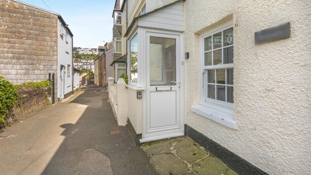 Une rue étroite avec un bâtiment blanc doté d’une porte et de fenêtres.