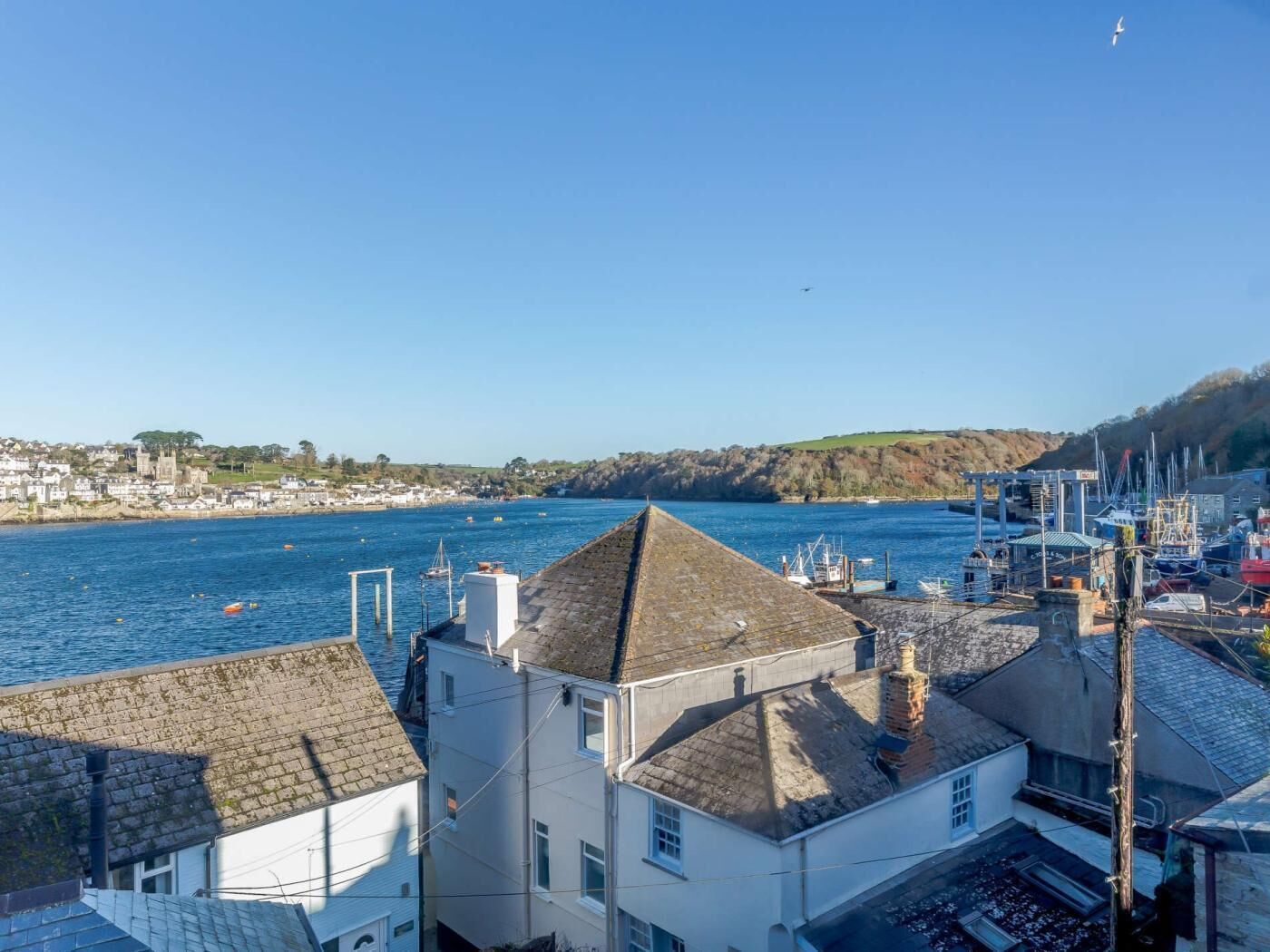 Une ville côtière dotée d’un port de plaisance, de maisons aux toits en pente et d’un ciel d’un bleu éclatant.