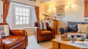 A cozy living room with leather sofas, a wooden coffee table, and a bookshelf. - 2 Bed in Polruan (oc-pc033) (Fowey)