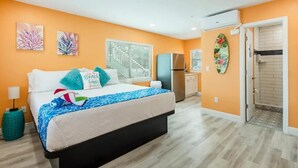 Une chambre à coucher comprenant un lit, une table de chevet, une fenêtre avec des stores, un réfrigérateur et un appareil de climatisation.