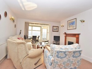 A living room with a sofa, armchair, television, fireplace, and a view through a window. - 3 Bed in Fowey (oc-pc008) (Fowey)