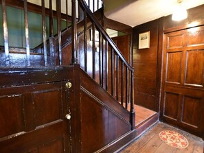 A wooden staircase with a handrail, a door with a brass handle, and a patterned floor. - 3 Bed in Polruan (oc-pc032) (Fowey)