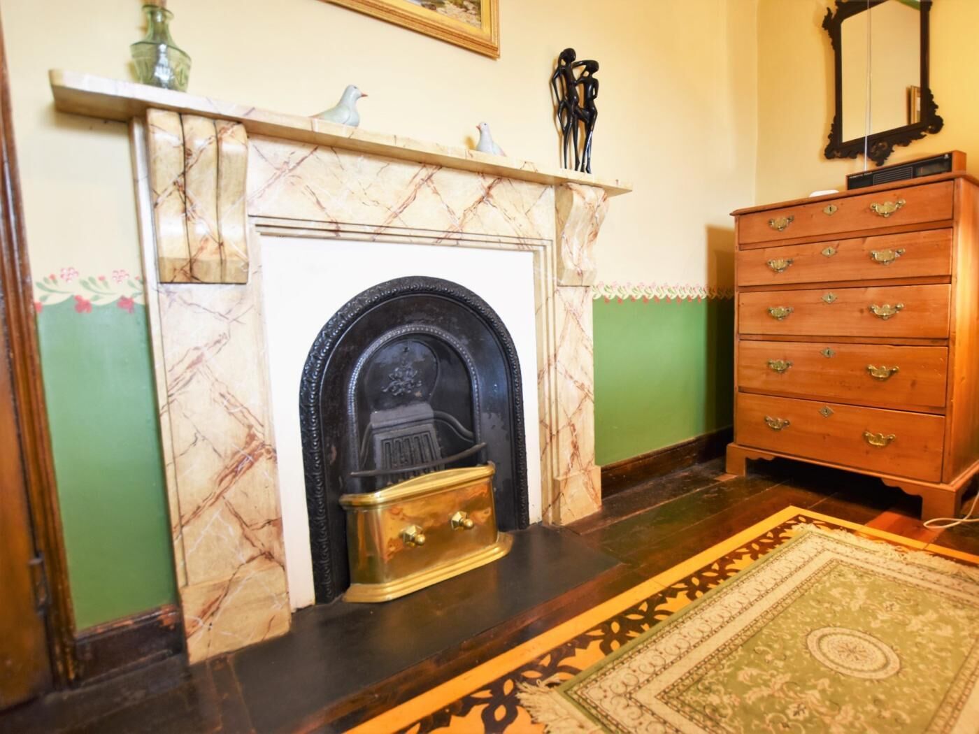 Une pièce avec une cheminée, une commode en bois et un tapis à motifs.