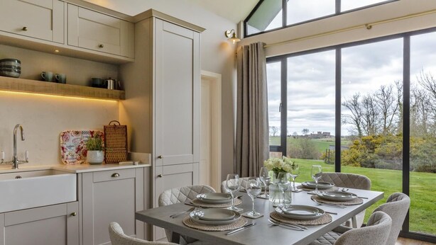 A modern kitchen with a dining area, large windows, and a view of the outdoors. - 3 Bed in Bamburgh (oc-61867) (Bamburgh)