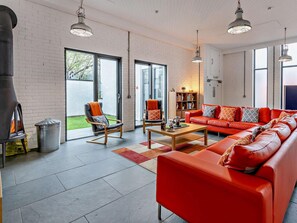 A modern living room with a red sofa, two rocking chairs, a coffee table, and a fireplace. - 3 Bed in Port Talbot (oc-61230) (Port Talbot)
