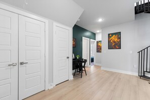 A hallway with white doors, a dining area with a table and chairs, and artwork on the walls. - SA's Best Downtown Location - Terrace, Jazz Themed (San Antonio)