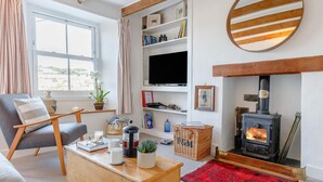 Een gezellige woonkamer met een open haard, een televisie en een comfortabele zithoek.