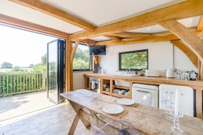 A wooden interior with a kitchen area, a dining table, and a view of the outdoors. - 1 Bed in Barnstaple (oc-62134) (Swimbridge)