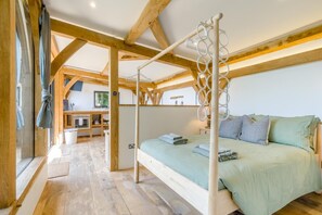 A bedroom with a four-poster bed, wooden beams, a small kitchenette, and a view of the outdoors. - 1 Bed in Barnstaple (oc-62134) (Swimbridge)