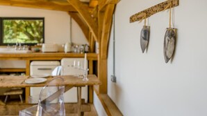 Ein Essbereich mit Holztisch, Stühlen und einer weißen Wand mit zwei aufgehängten Objekten.