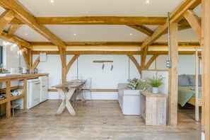 A rustic kitchen with wooden beams, a dining table, and a white sofa.